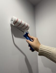 Rodillo encolando pared blanca